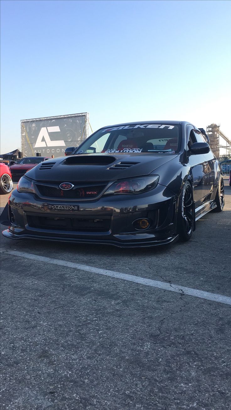 a black car parked in a parking lot next to other cars