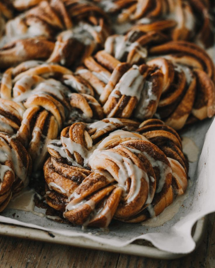 cinnamon rolls with icing sitting on top of a pan