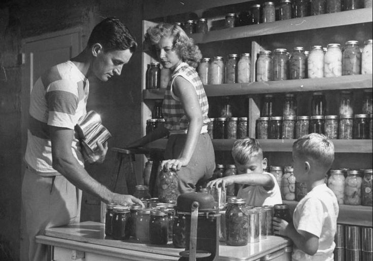 an old black and white photo of three people in front of shelves full of jars