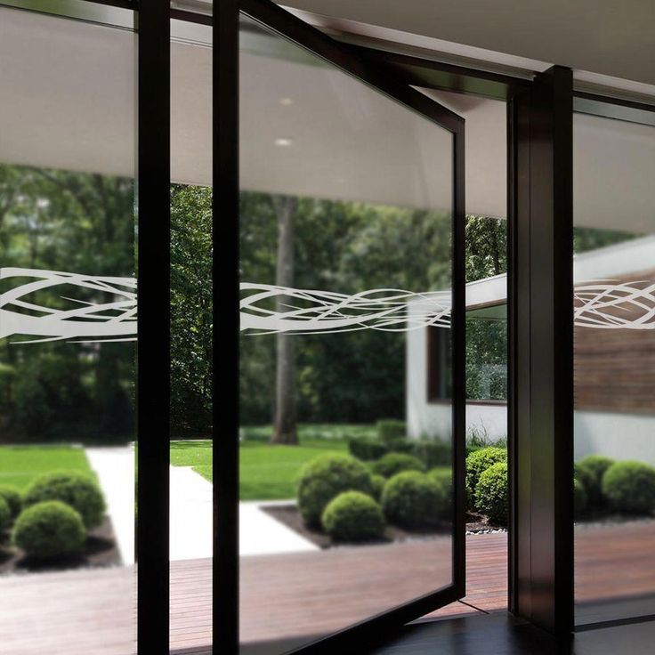 an open glass door leading to a large yard with trees and bushes in the background