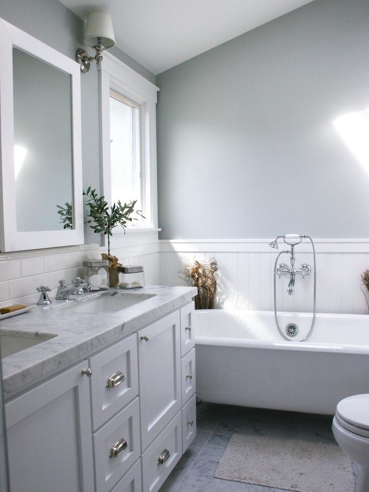 a bathroom with a white tub, sink and toilet next to a mirror on the wall