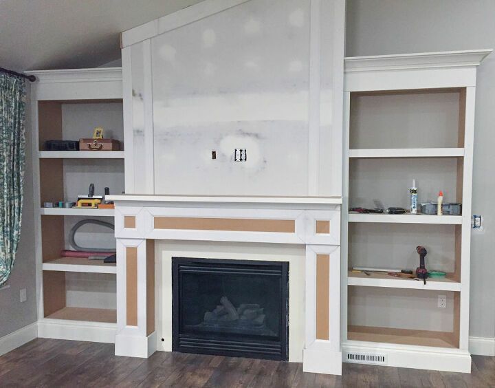 an empty living room with built - in bookshelves and fireplace