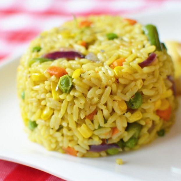 a white plate topped with rice and veggies on top of a red checkered table cloth