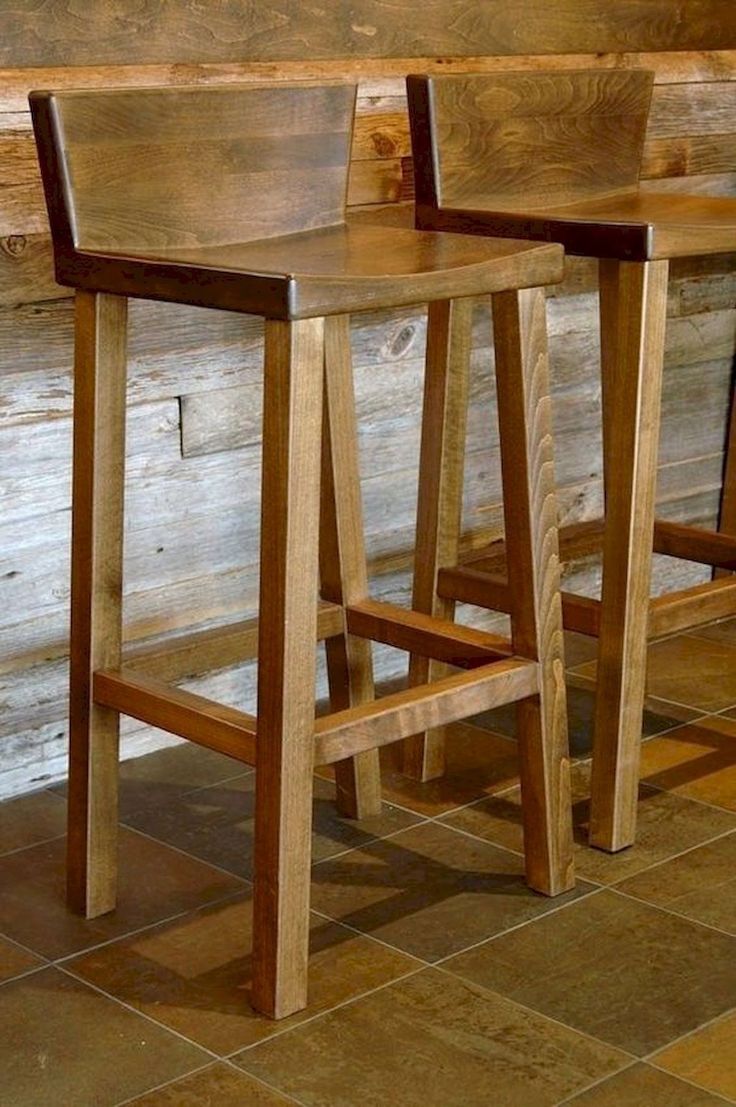 two wooden stools sitting next to each other on top of a tile floor in front of a wooden wall