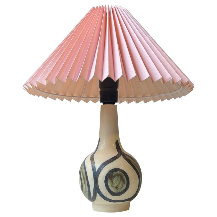 a table lamp with a pink shade on it's base and a circular design on the bottom