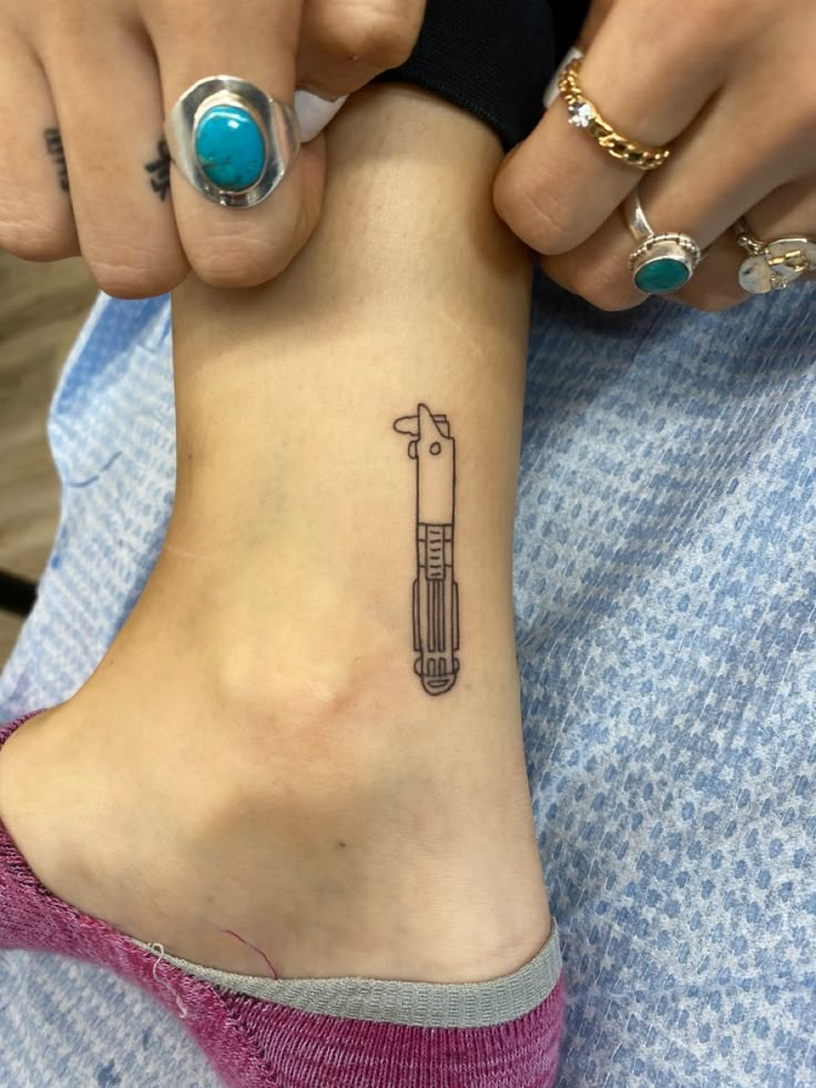 a woman is getting her tattoo done on her foot with a needle and an arrow