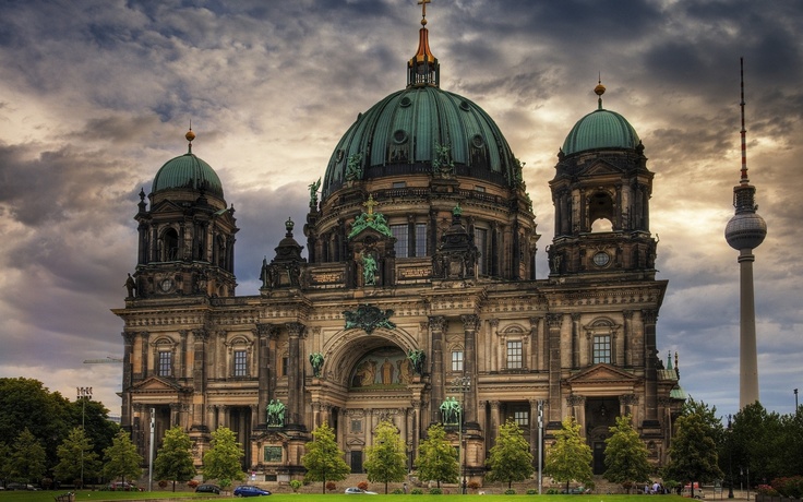 the large building has two towers on it's sides and is surrounded by green grass