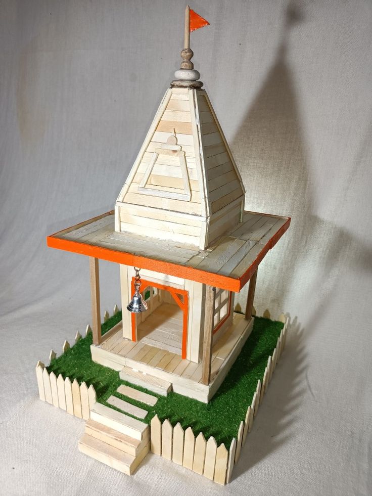 a small wooden structure with an orange flag on top and green grass around the base