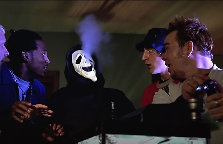 a group of men standing around each other in front of a white mask on their face