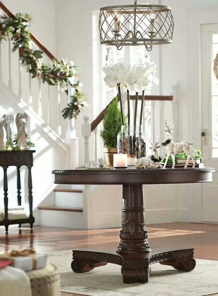 a table with flowers and candles on it in front of the stairs, next to a stair case