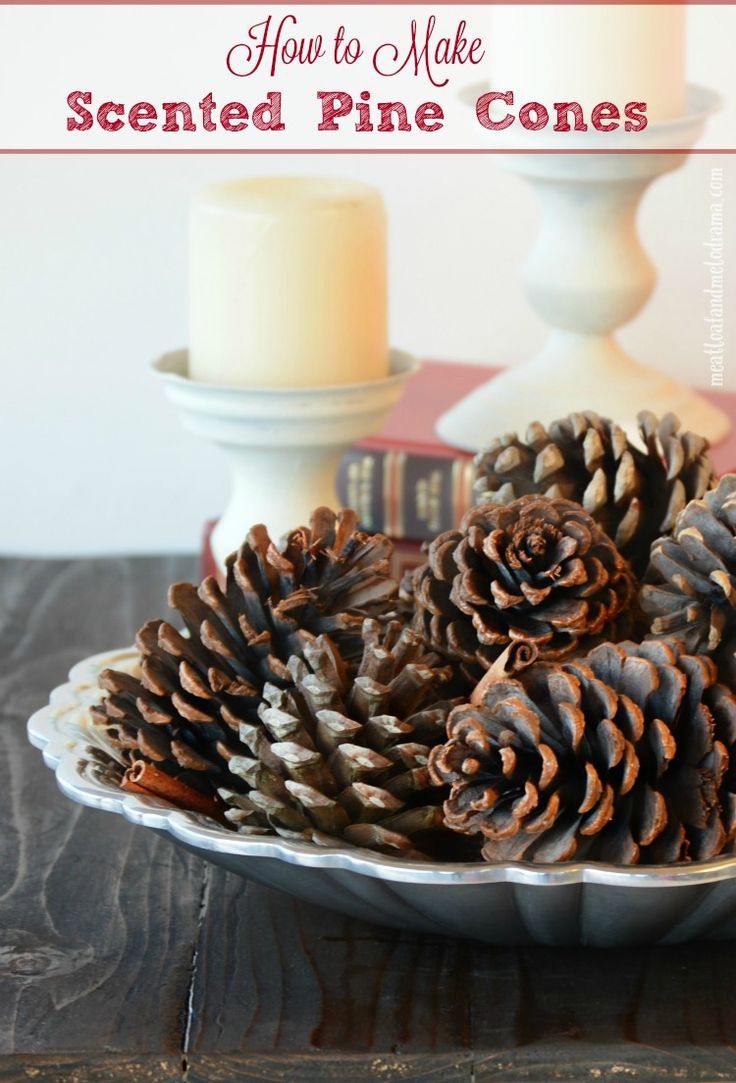 some pine cones are in a bowl on a table next to a candle and books