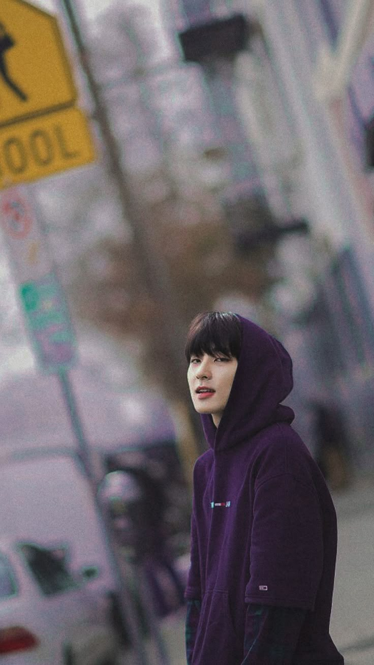 a young man in a purple hoodie is walking down the street