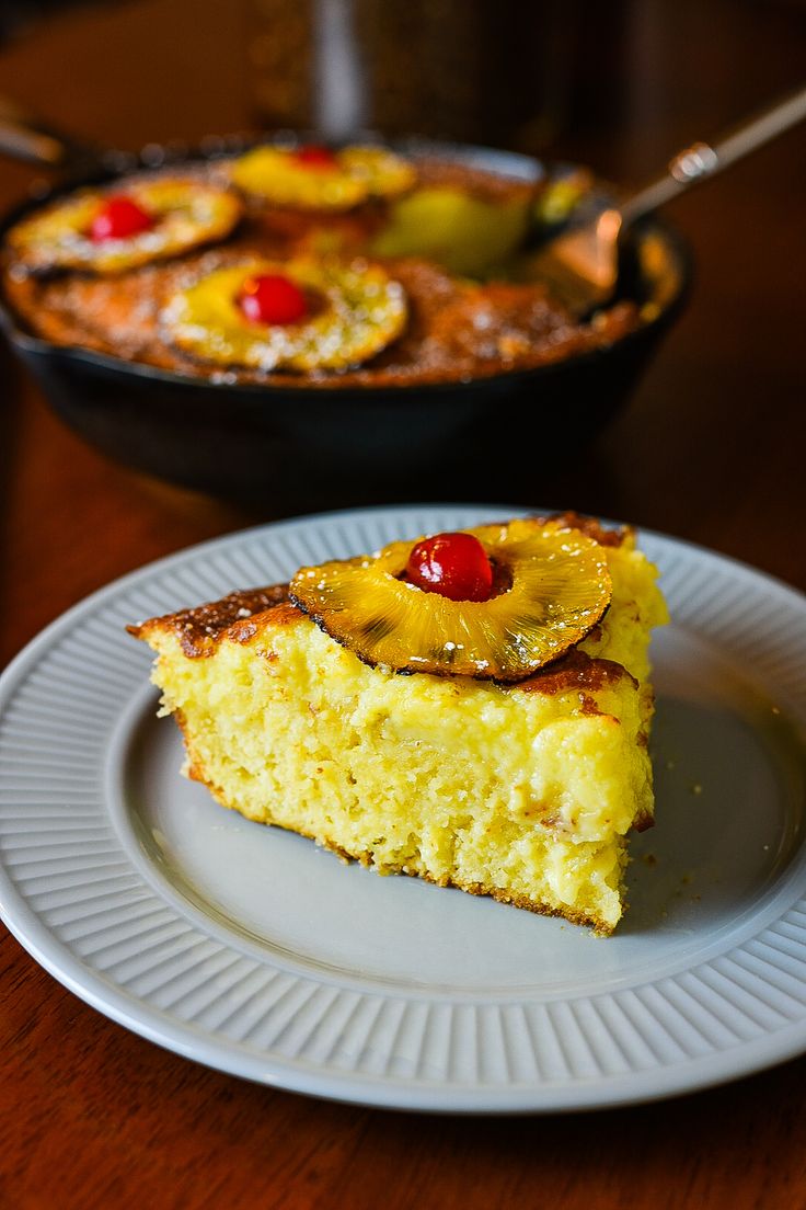 a piece of pineapple upside down cake on a plate next to a skillet