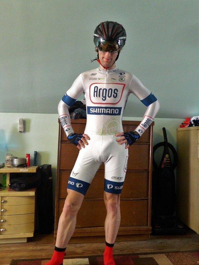 a man wearing a bike suit and helmet standing in front of a dresser with his hands on his hips