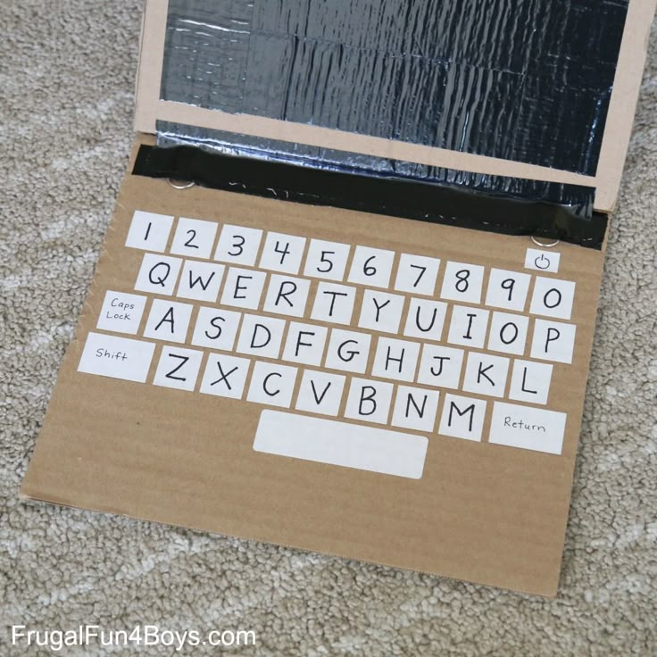 an open laptop computer sitting on top of a cardboard box covered in letters and numbers