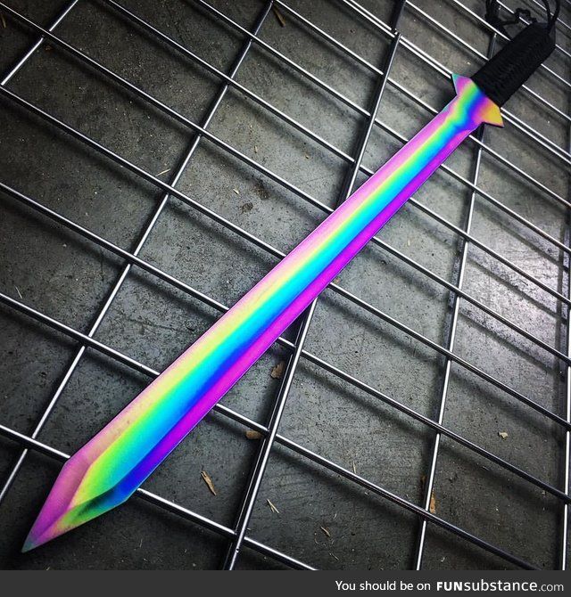 a rainbow colored toothbrush laying on top of a metal grate with black handle