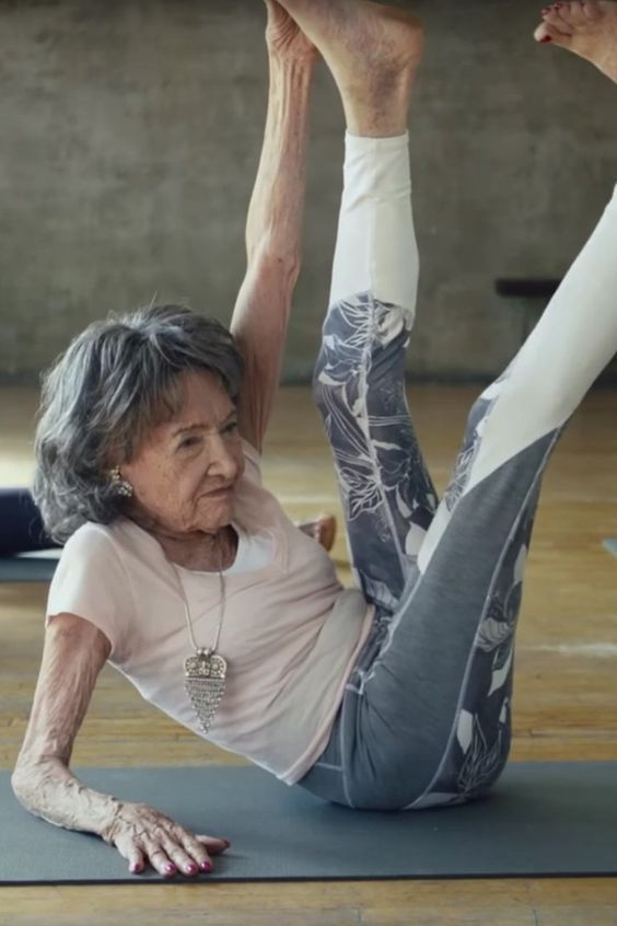 an older woman doing yoga on a mat