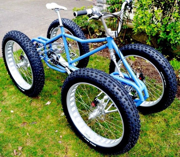 a blue and white bike sitting on top of green grass next to a bush in front of a house