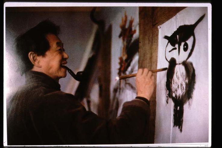 a man is painting an owl on the wall