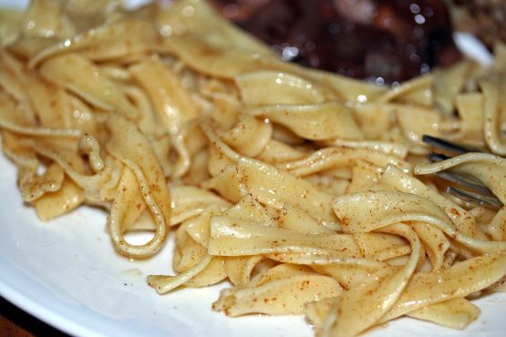 a white plate topped with pasta and meat covered in gravy next to a fork