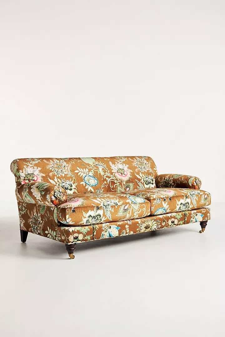 an orange floral couch sitting on top of a white floor next to a wooden frame