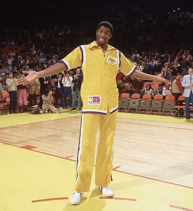 a man standing on top of a basketball court holding his arms out to the side