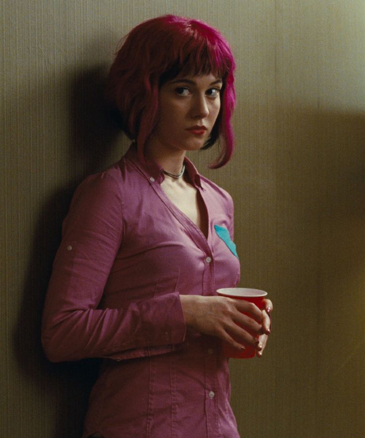 a woman with pink hair is holding a cup