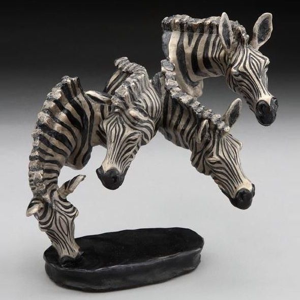 two zebra figurines are standing on top of a black base and one has its head in the air