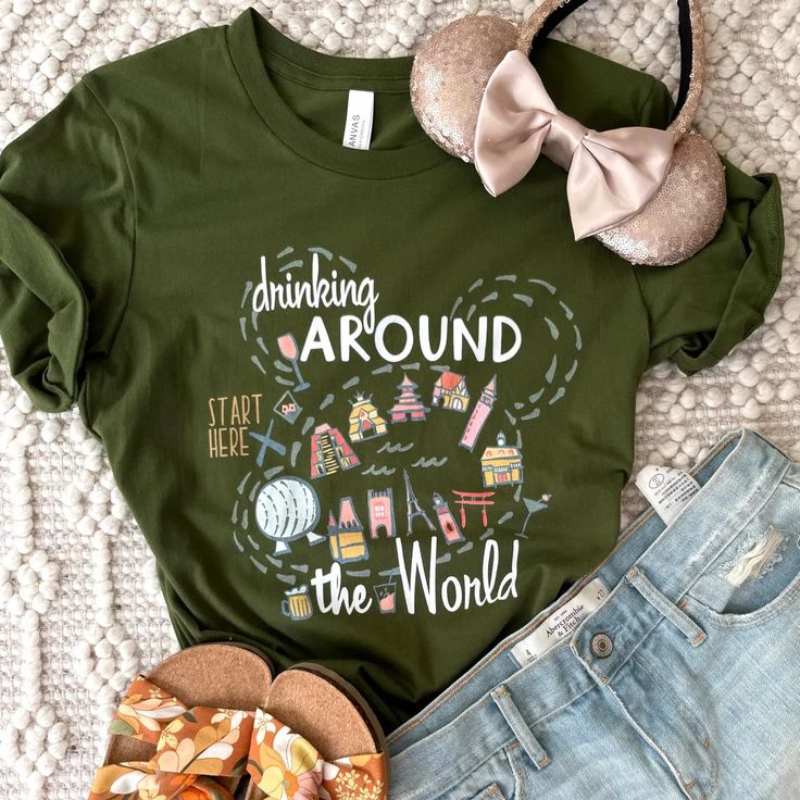 a green shirt with the words hiking around the world on it next to some shoes