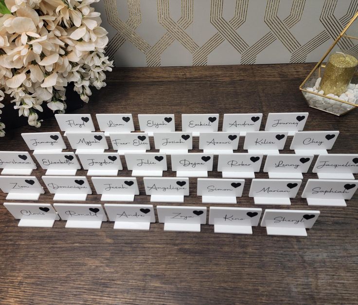 place cards are arranged on a table with flowers and vases in the back ground