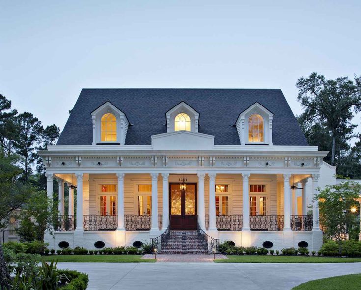 a large white house with two stories and lots of windows on the second story is lit up at night