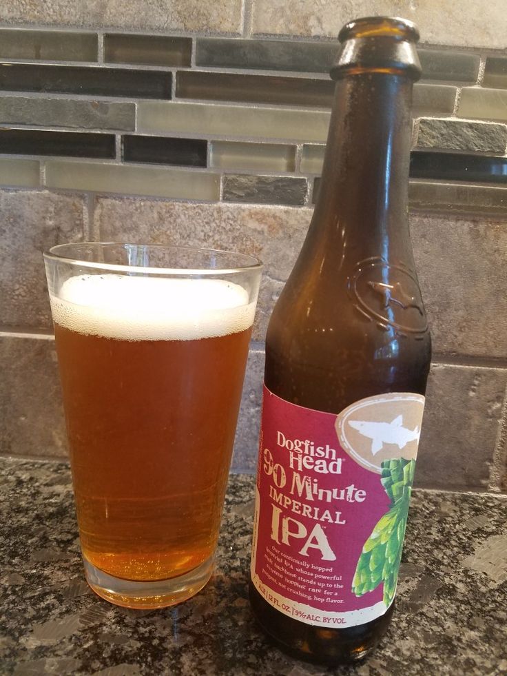 a bottle of beer sitting next to a glass filled with liquid on top of a counter