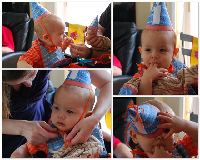 the baby is wearing a birthday hat and being held by his mother, who also has an orange ribbon on it's head