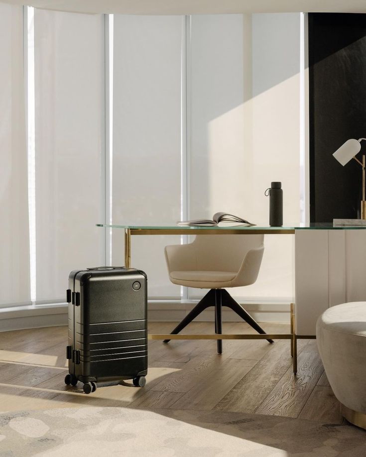 a suitcase is sitting in front of a glass table with a chair and lamp on it