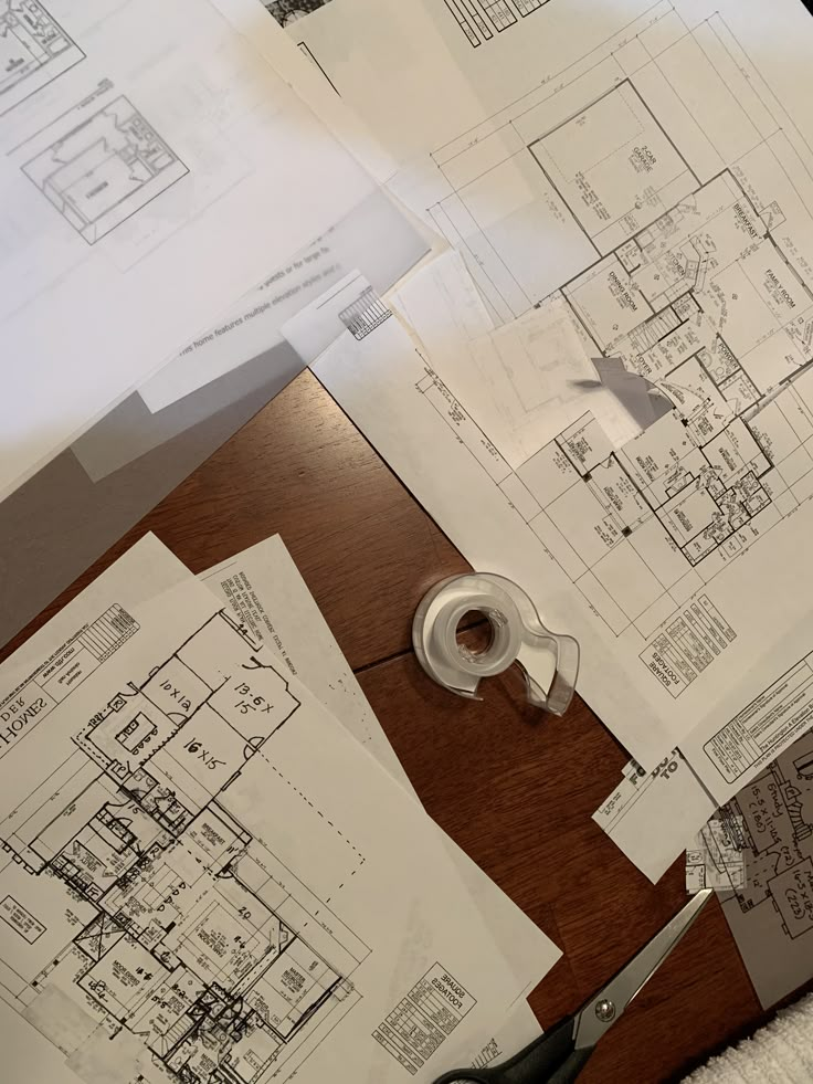 some papers and scissors on a table with drawings, tape and paper cutters next to them