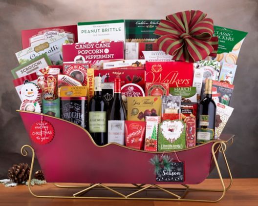 a red sleigh filled with lots of wine and assorted christmas gifts on a table