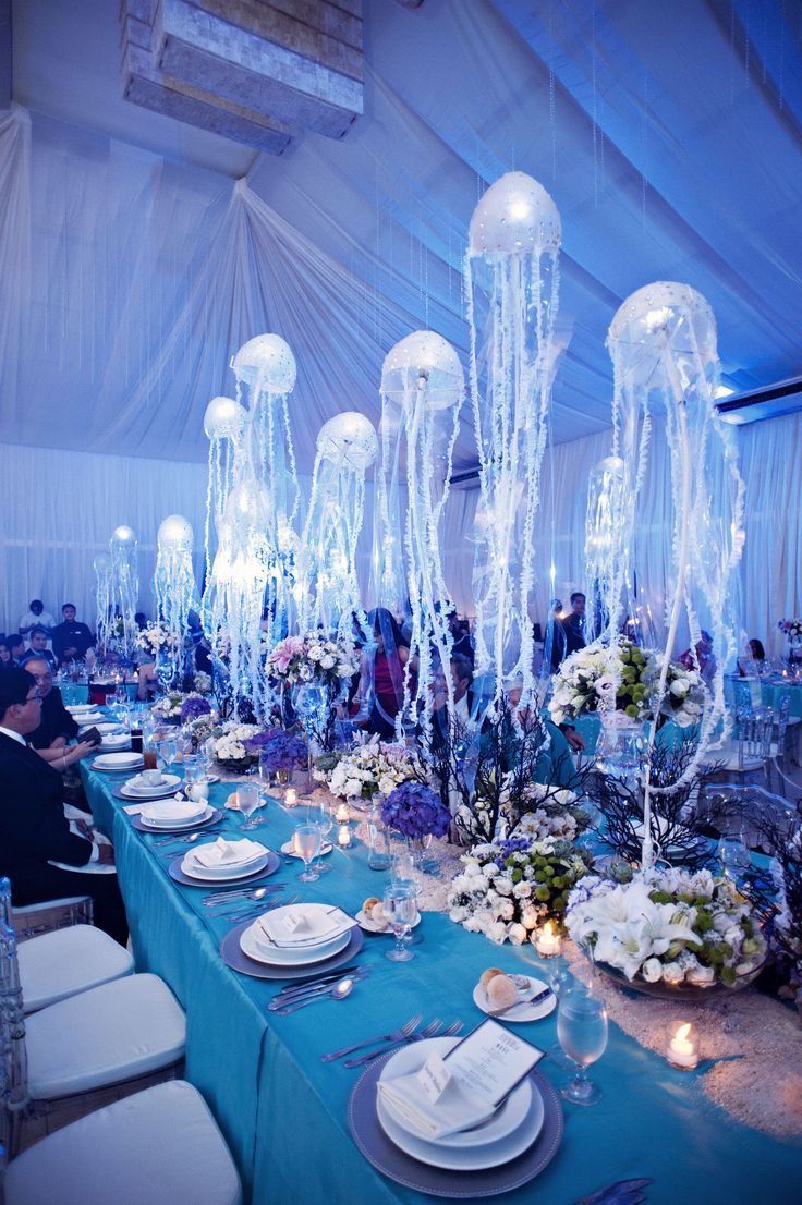 the tables are set with white plates and place settings for an ocean themed dinner party