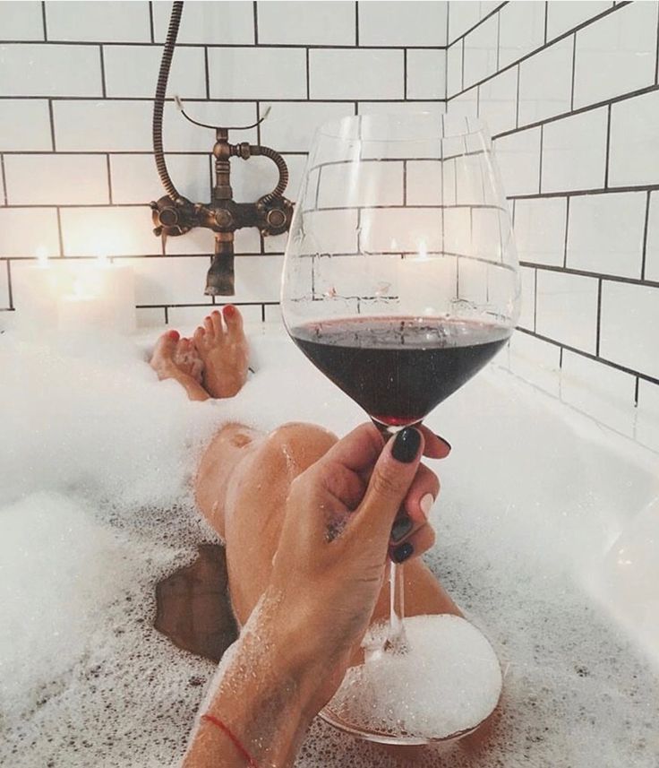 a person is taking a bath with a glass of wine