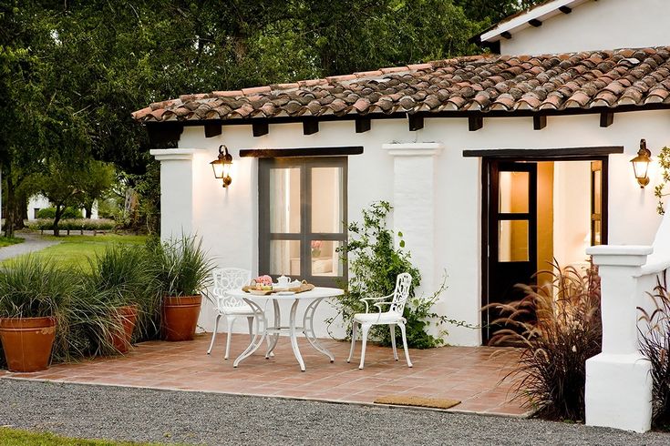 a small white house with a table and chairs on the outside patio area in front of it