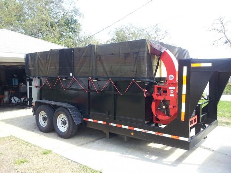 a large black dump truck parked in front of a house with tarp covering it's sides