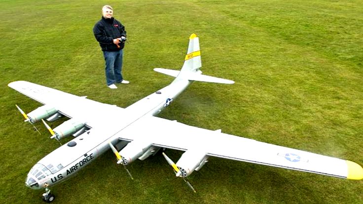 a man standing next to an airplane on top of a lush green field