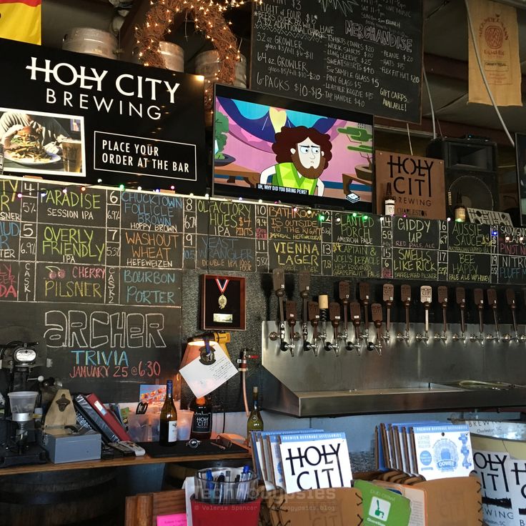 there are many signs on the wall above the bar and behind it is a beer tap