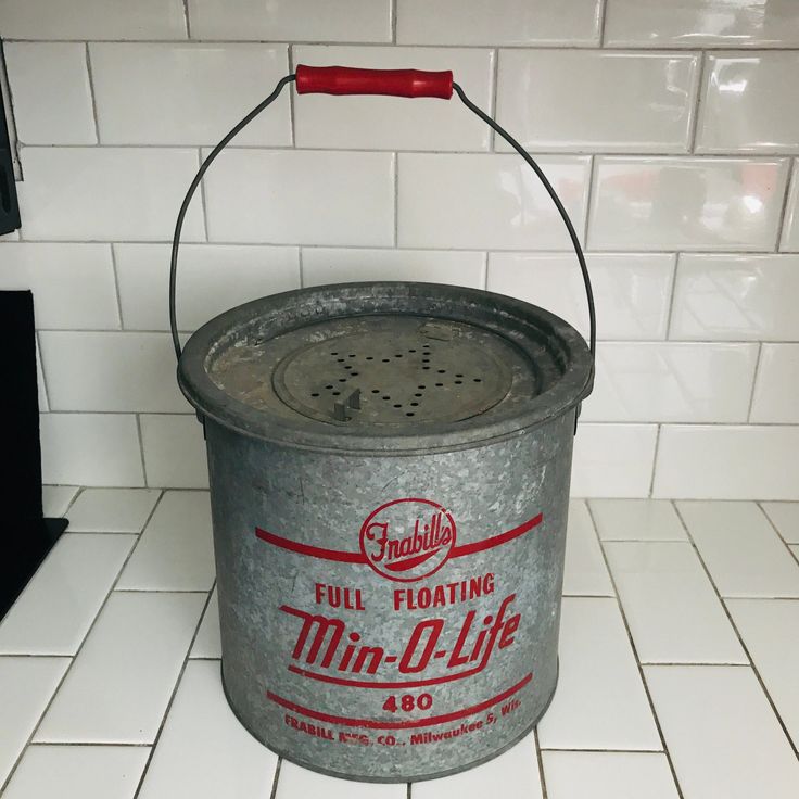 a metal bucket sitting on top of a white tiled floor