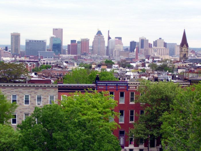 a view of the city skyline with trees and buildings in the foreground, taken from an overlook point