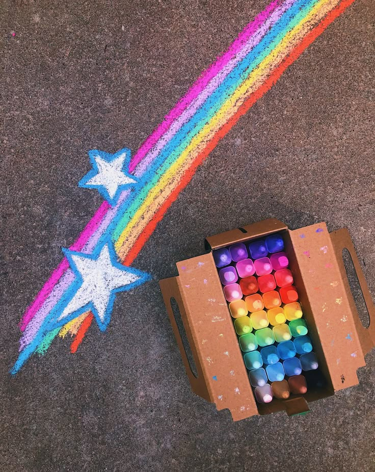 a cardboard box filled with colored crayons and stars on the ground next to it