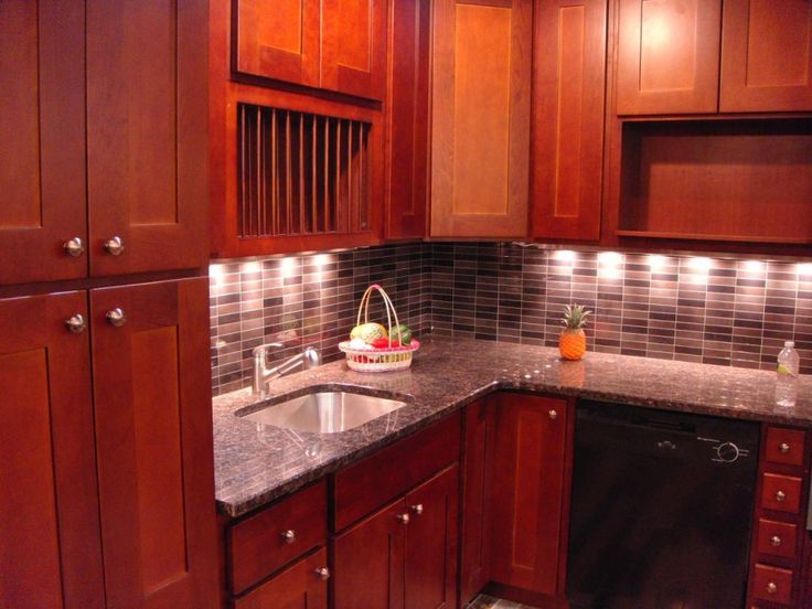 a kitchen with dark wood cabinets and granite counter tops is lit by recessed lighting