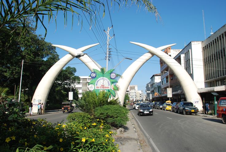 an arch in the middle of a street with cars parked on it's sides