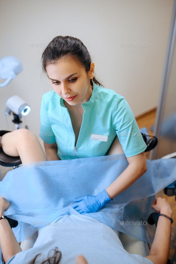 a woman in blue scrubs sitting on a hospital bed