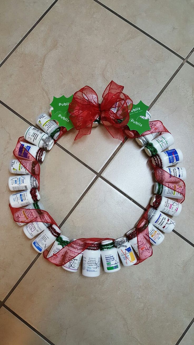 a wreath made out of medicine bottles on the floor with a red ribbon around it