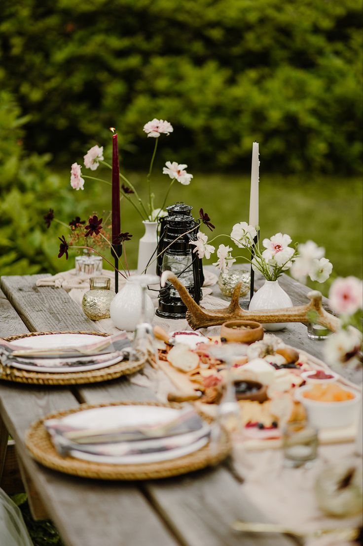 the table is set with plates and silverware, candles and flowers in vases